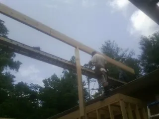 Carpenter setting a ridge beam over a new addition frame — Ice Dam Removal by Roofing Brothers in Byers