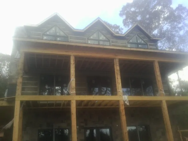 Dormers and porch framing on a large log home under construction — Roof Coating work by our crew in Byers