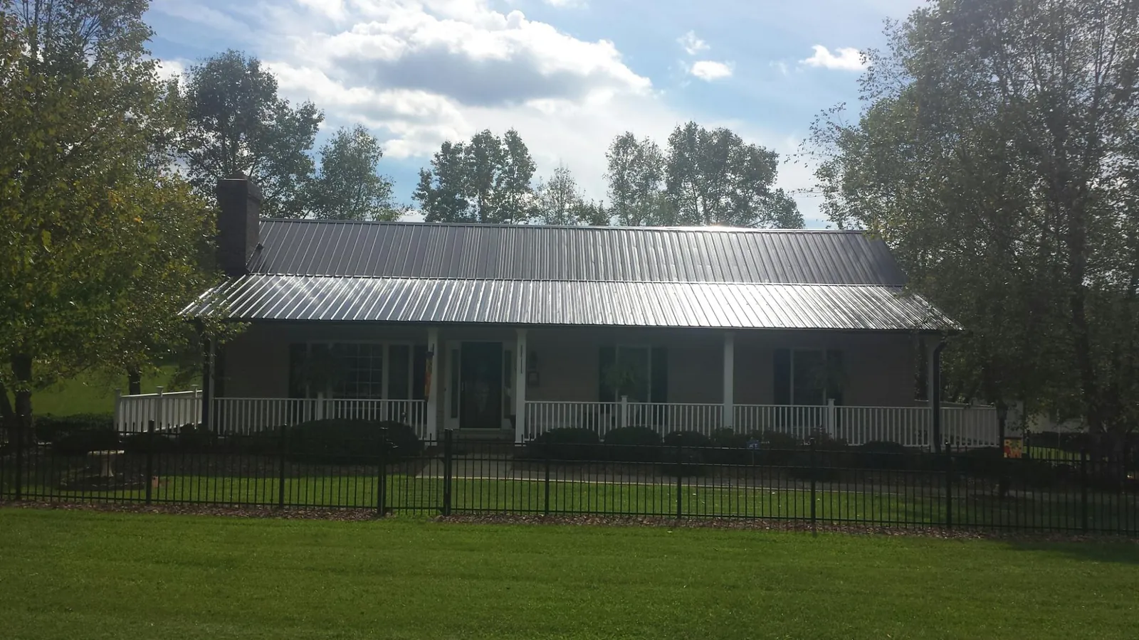 Gray metal roof on a brick ranch with a full width front porch — Gutter Guard Installation work by our crew in Byers