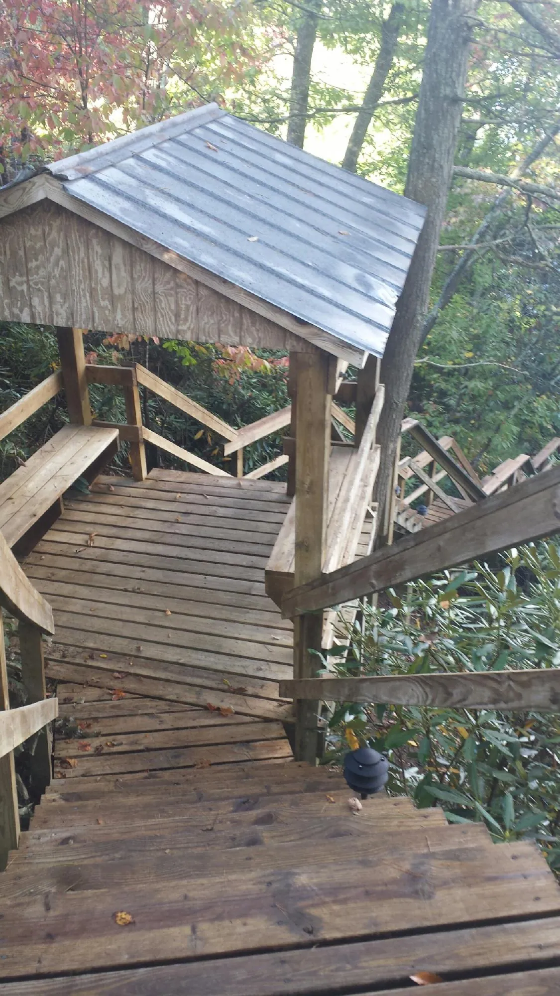 Metal roofed shelter over wooden steps on a wooded walkway — Skylight Repair & Installation work by our crew in Byers