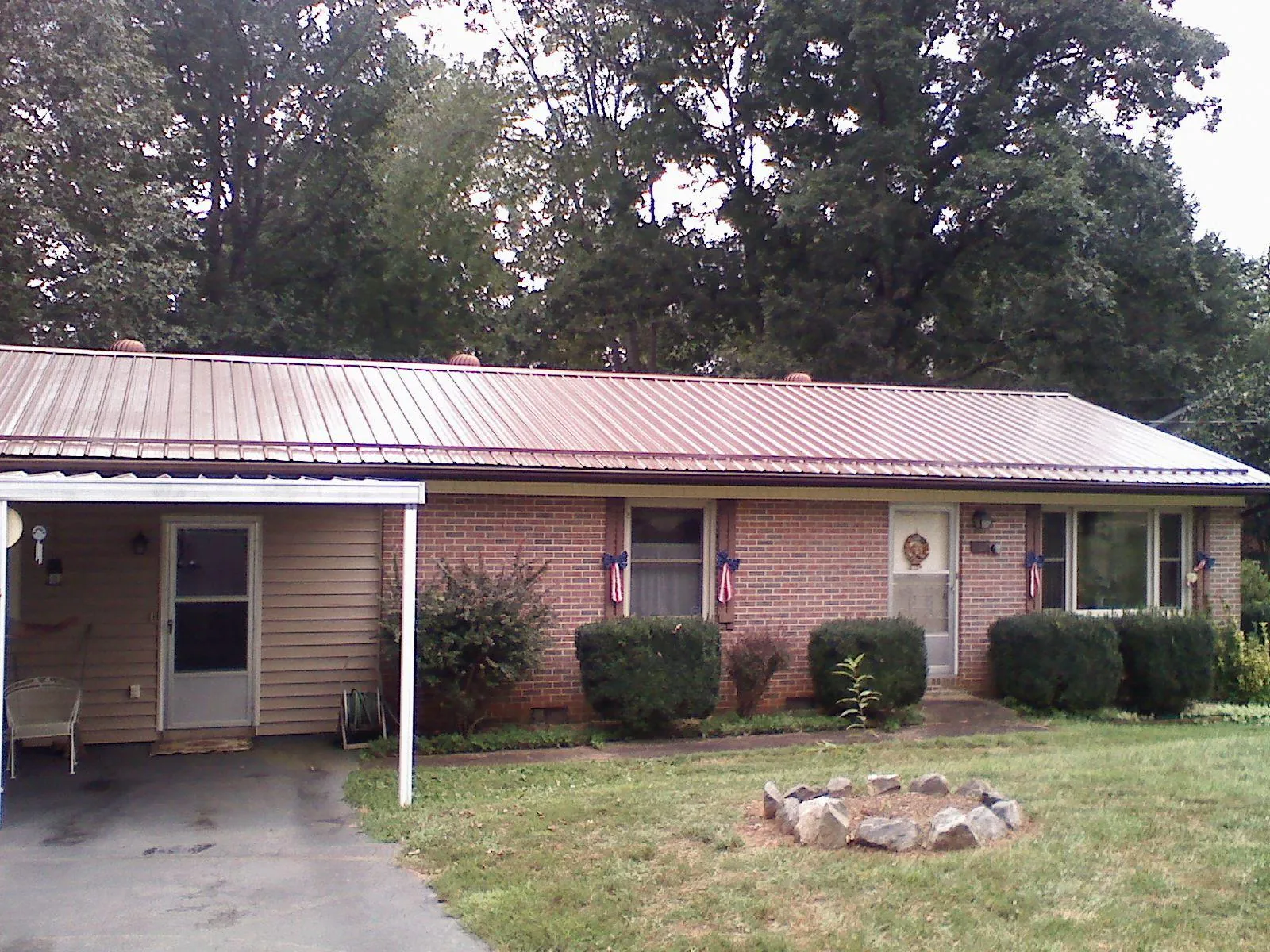 Bronze metal roof and carport on a brick ranch home — Roof Repair work by our crew in Byers