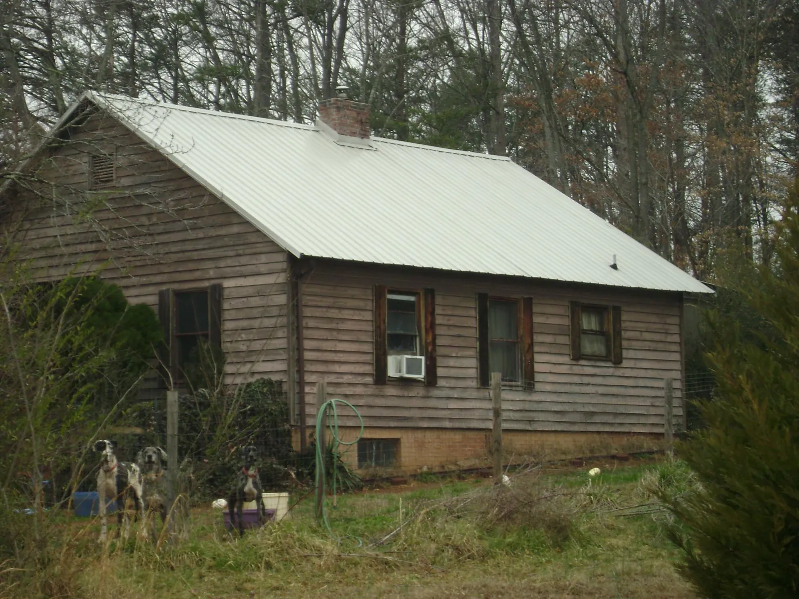 White metal roof on an old wood sided farmhouse, from a Metal Roof Installation job in Byers