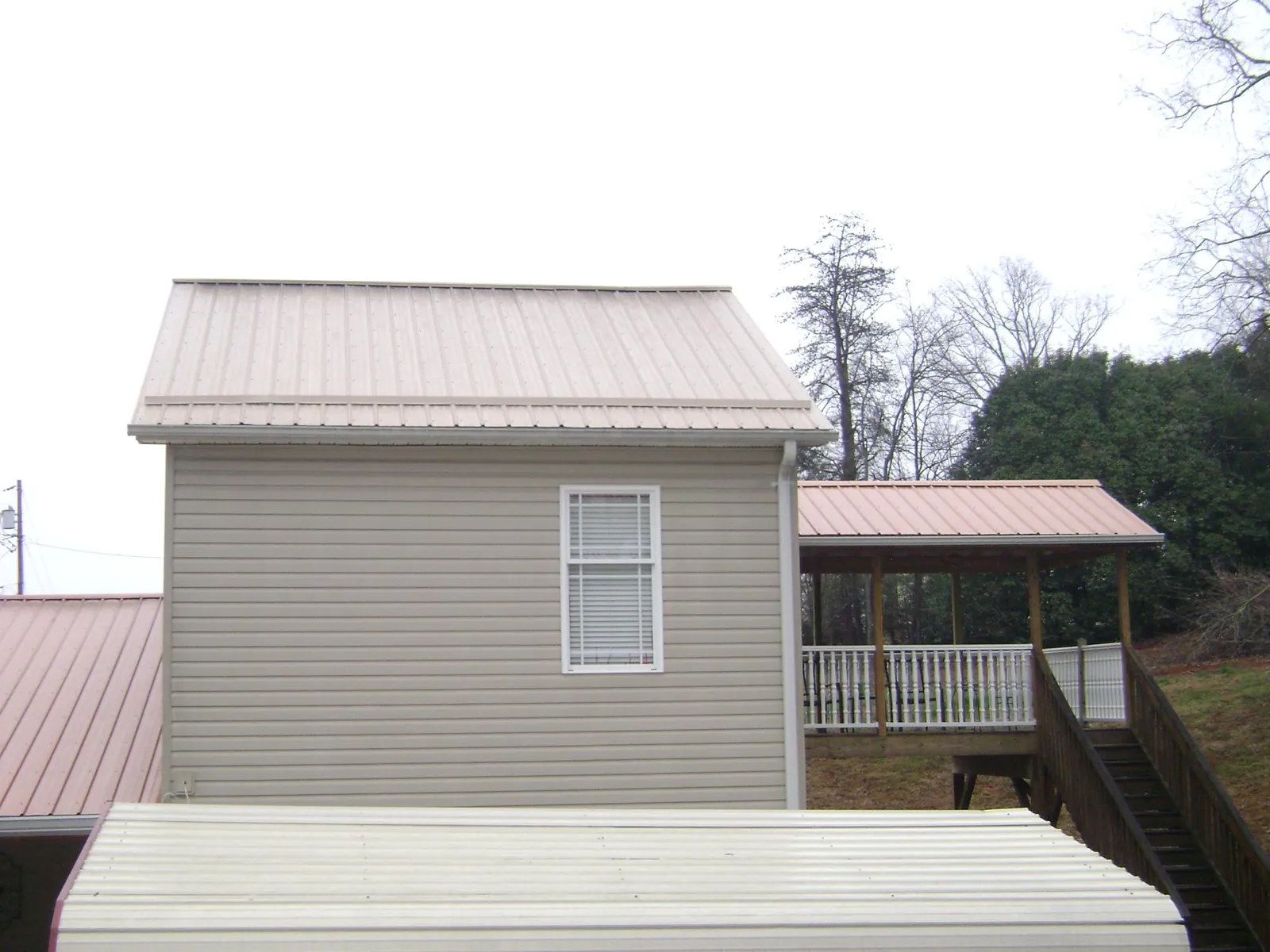 Tan metal roofs on a two story addition and attached porch in Byers