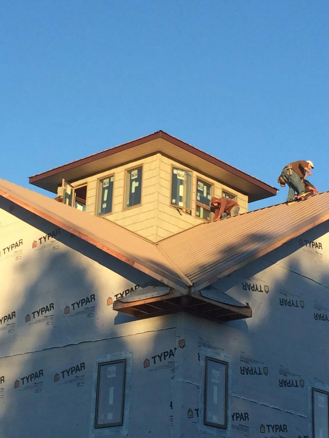 Roofers working around a rooftop cupola on a new metal roof at sunset — Roof Waterproofing in Byers by Roofing Brothers